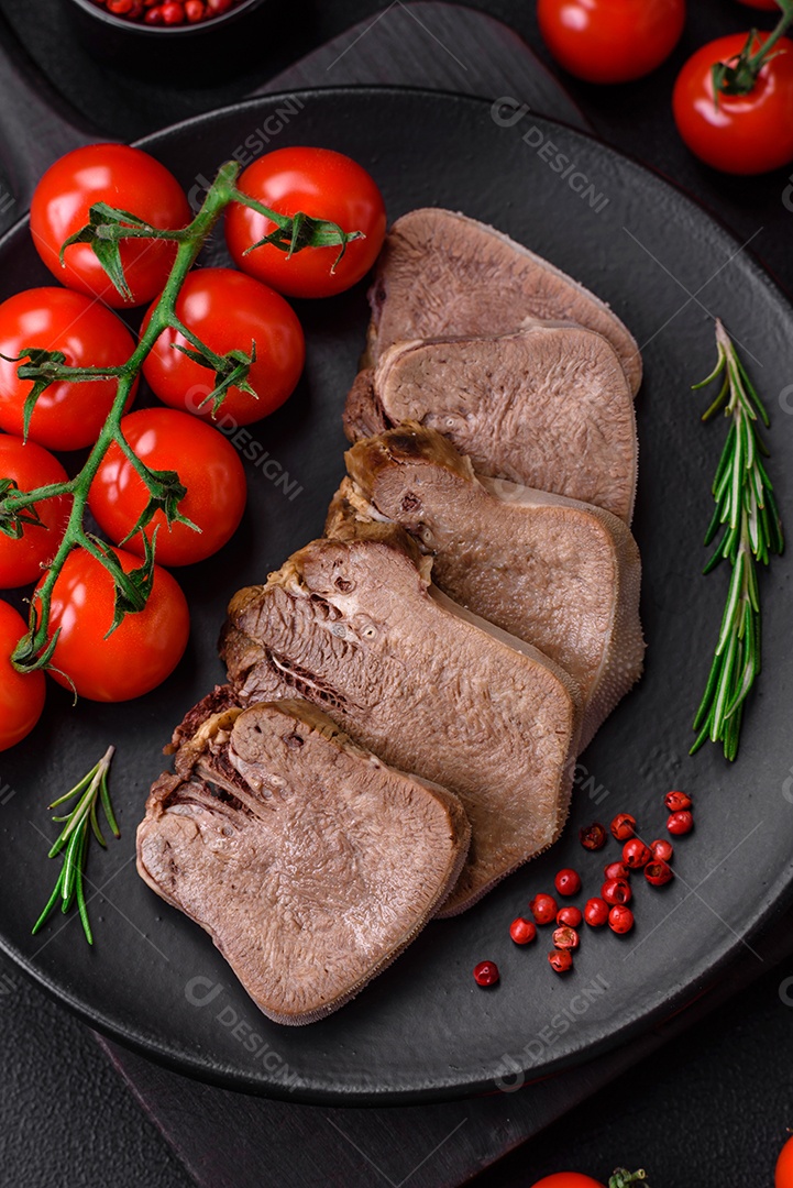 Deliciosa língua de boi cozida cortada com legumes e especiarias em um fundo escuro de concreto