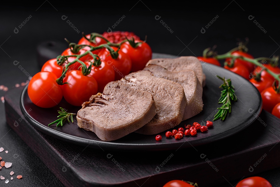 Deliciosa língua de boi cozida cortada com legumes e especiarias em um fundo escuro de concreto