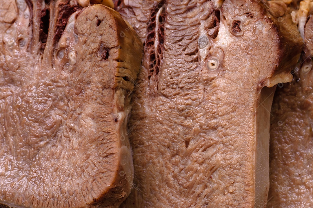 Deliciosa língua de boi cozida cortada com legumes e especiarias em um fundo escuro de concreto