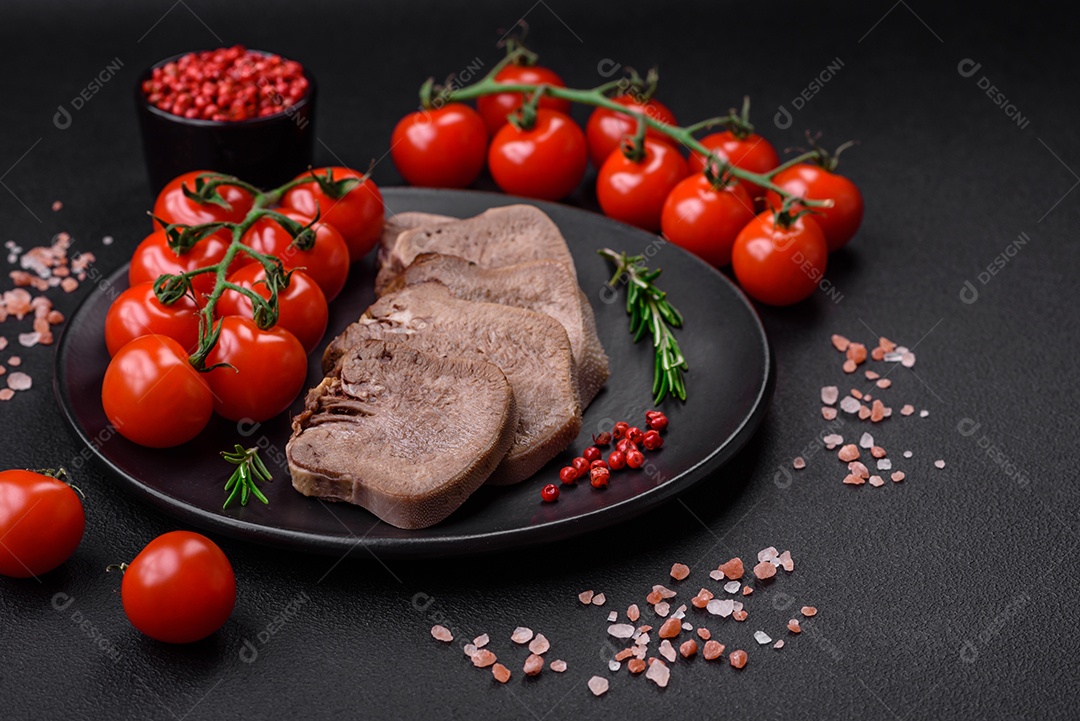 Deliciosa língua de boi cozida cortada com legumes e especiarias em um fundo escuro de concreto