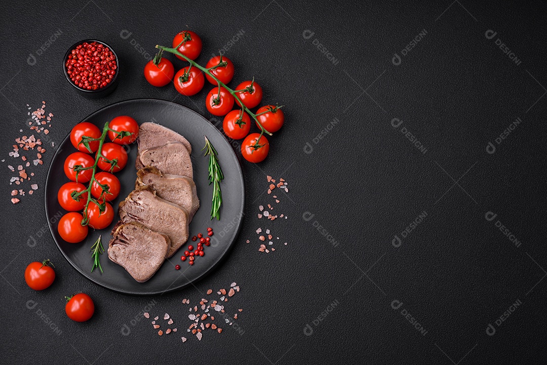 Deliciosa língua de boi cozida cortada com legumes e especiarias em um fundo escuro de concreto