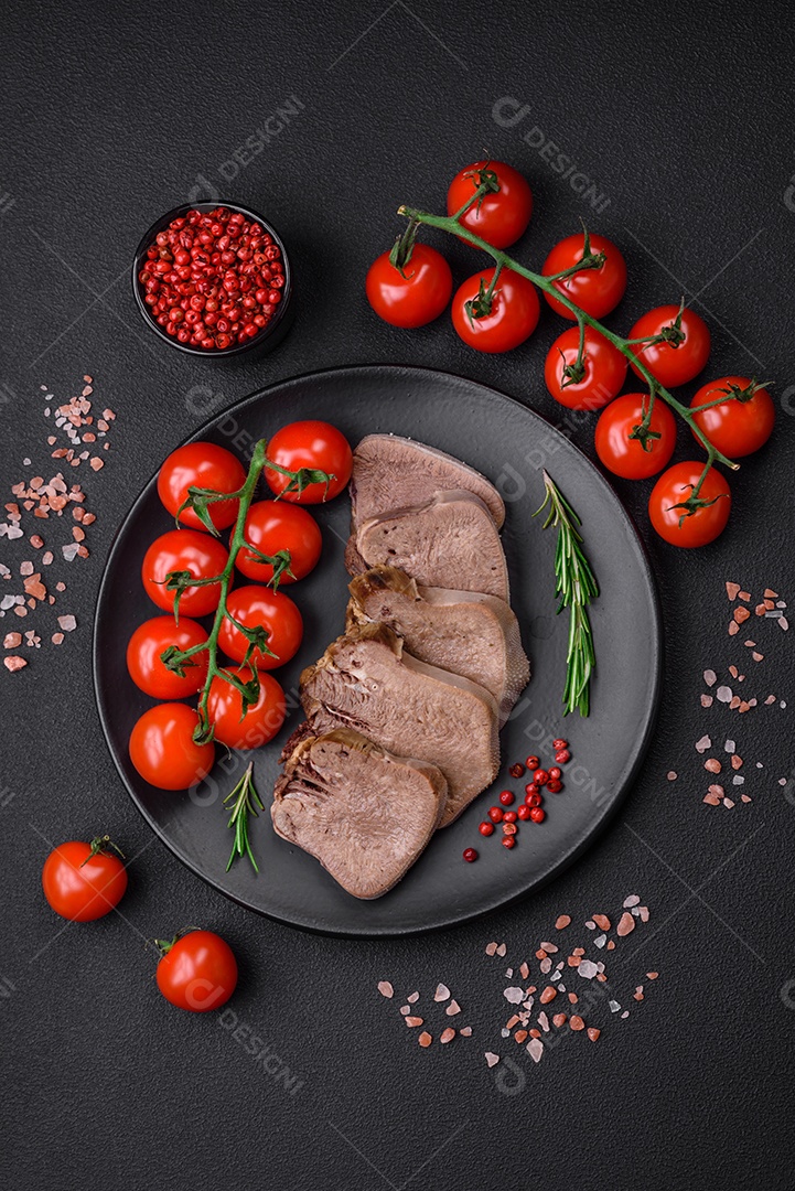 Deliciosa língua de boi cozida cortada com legumes e especiarias em um fundo escuro de concreto