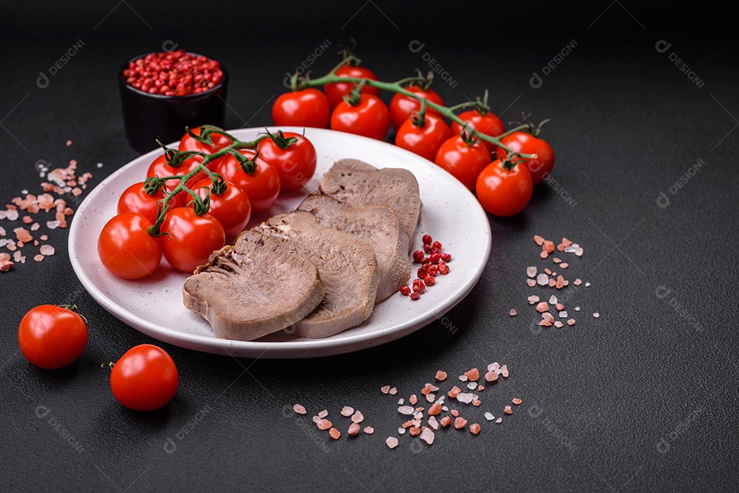 Deliciosa língua de boi cozida cortada com legumes e especiarias em um fundo escuro de concreto