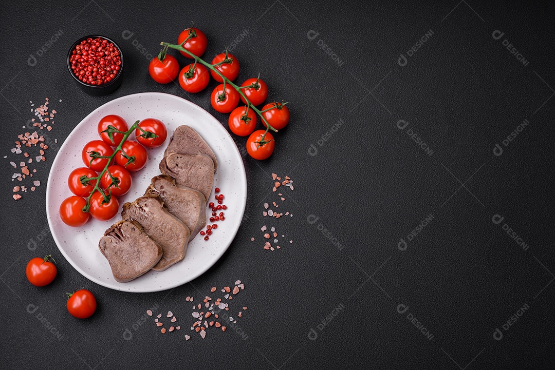 Deliciosa língua de boi cozida cortada com legumes e especiarias em um fundo escuro de concreto