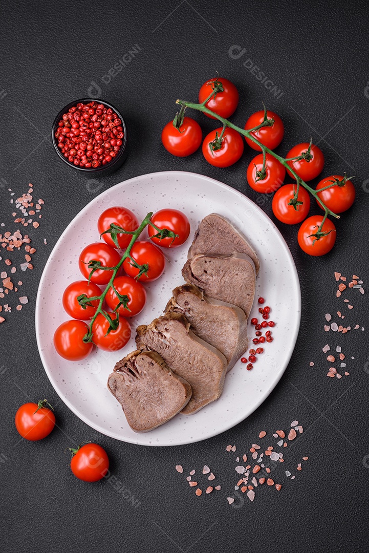 Deliciosa língua de boi cozida cortada com legumes e especiarias em um fundo escuro de concreto