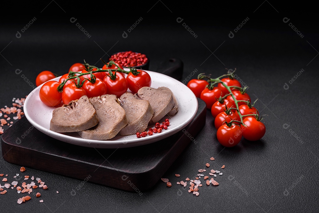 Deliciosa língua de boi cozida cortada com legumes e especiarias em um fundo escuro de concreto