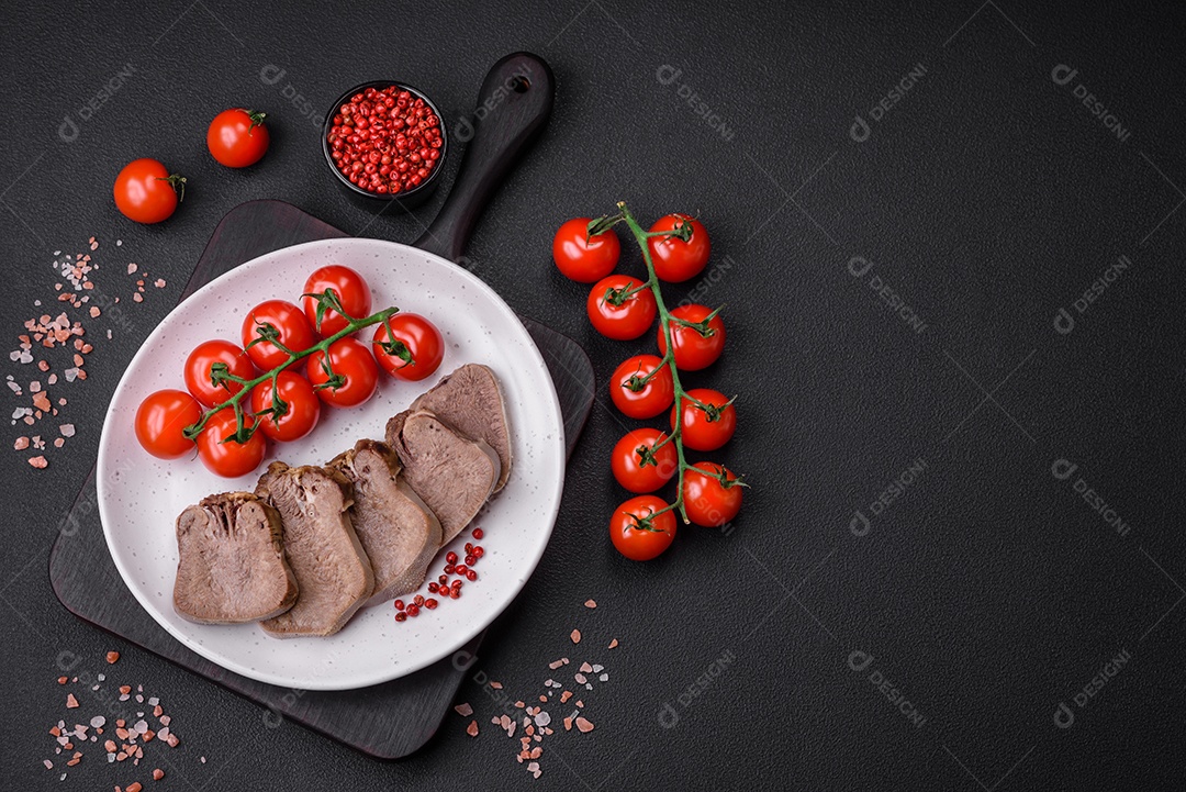 Deliciosa língua de boi cozida cortada com legumes e especiarias em um fundo escuro de concreto