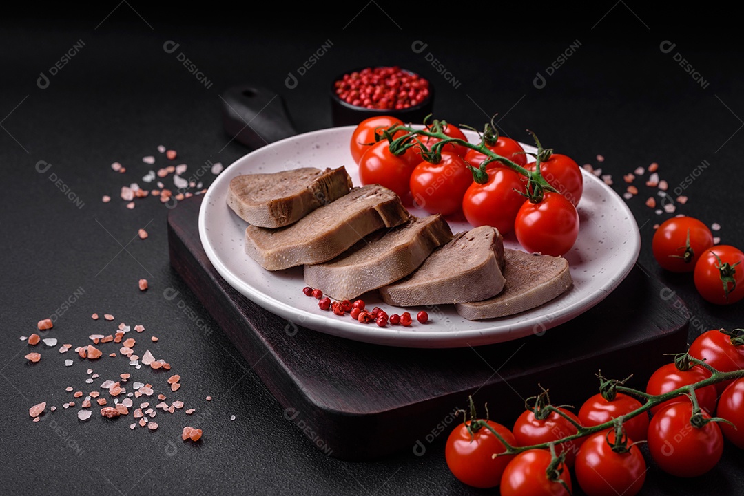 Deliciosa língua de boi cozida cortada com legumes e especiarias em um fundo escuro de concreto