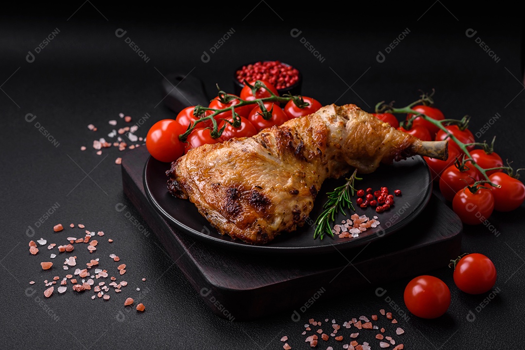 Perna de frango grelhado fresco com sal, especiarias e ervas sobre um fundo escuro de concreto