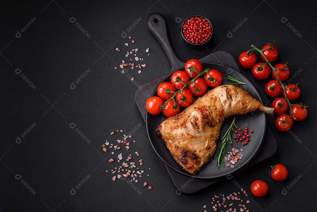 Perna de frango grelhado fresco com sal, especiarias e ervas sobre um fundo escuro de concreto