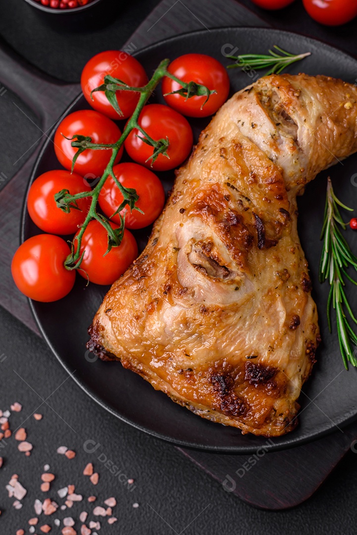 Perna de frango grelhado fresco com sal, especiarias e ervas sobre um fundo escuro de concreto
