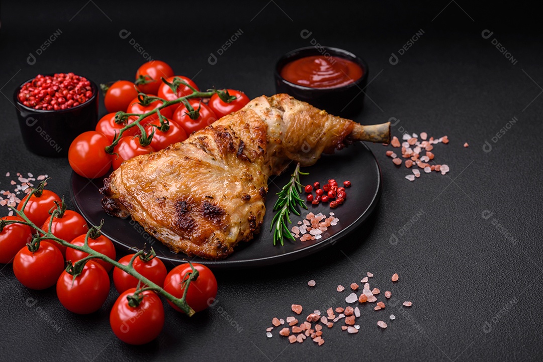 Perna de frango grelhado fresco com sal, especiarias e ervas sobre um fundo escuro de concreto