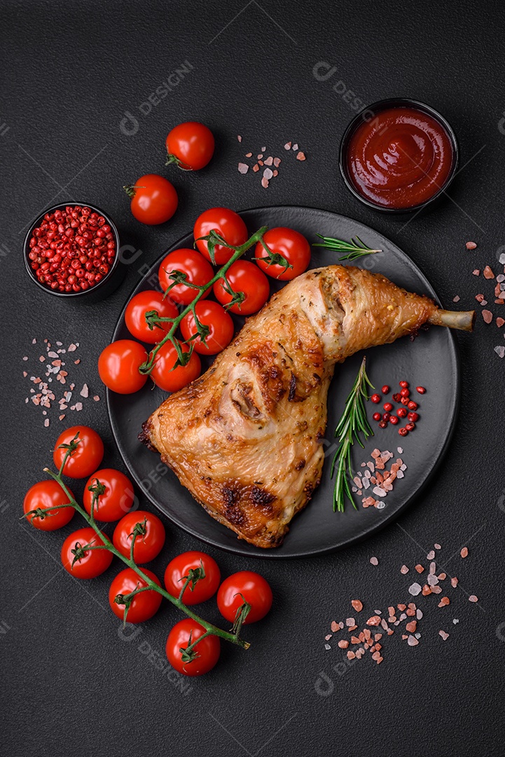 Perna de frango grelhado fresco com sal, especiarias e ervas sobre um fundo escuro de concreto