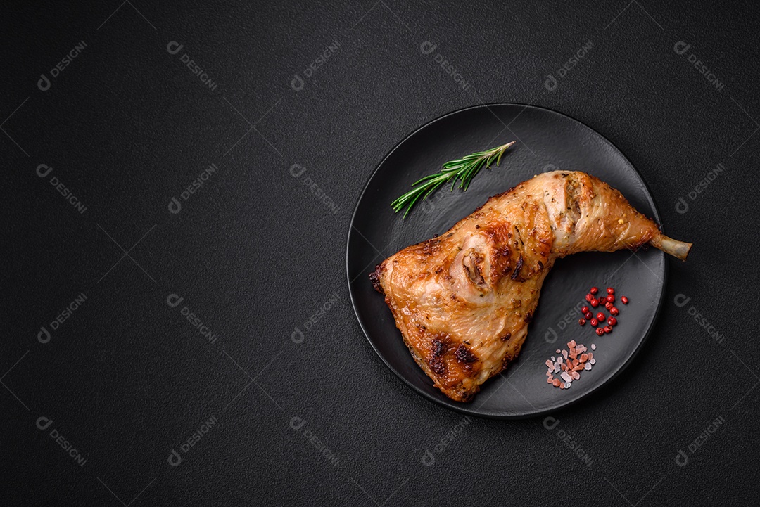 Perna de frango grelhado fresco com sal, especiarias e ervas sobre um fundo escuro de concreto