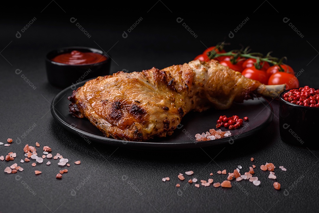 Perna de frango grelhado fresco com sal, especiarias e ervas sobre um fundo escuro de concreto