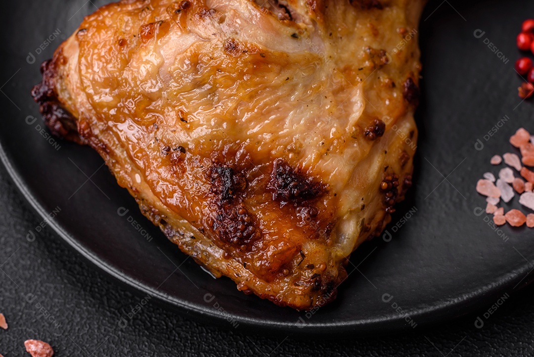 Perna de frango grelhado fresco com sal, especiarias e ervas sobre um fundo escuro de concreto