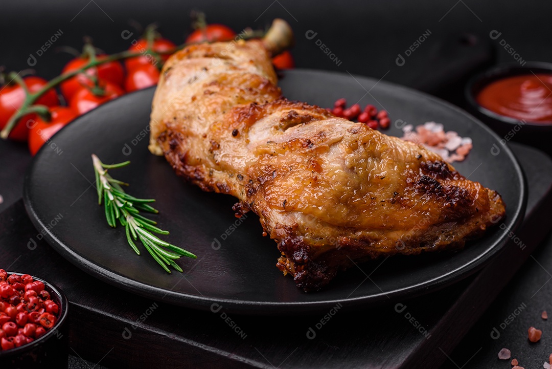 Perna de frango grelhado fresco com sal, especiarias e ervas sobre um fundo escuro de concreto