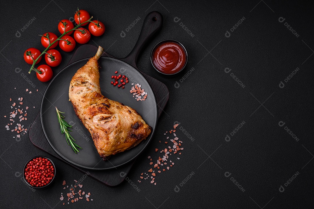 Perna de frango grelhado fresco com sal, especiarias e ervas sobre um fundo escuro de concreto