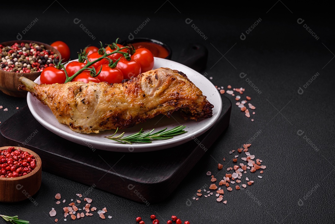 Perna de frango grelhado fresco com sal, especiarias e ervas sobre um fundo escuro de concreto