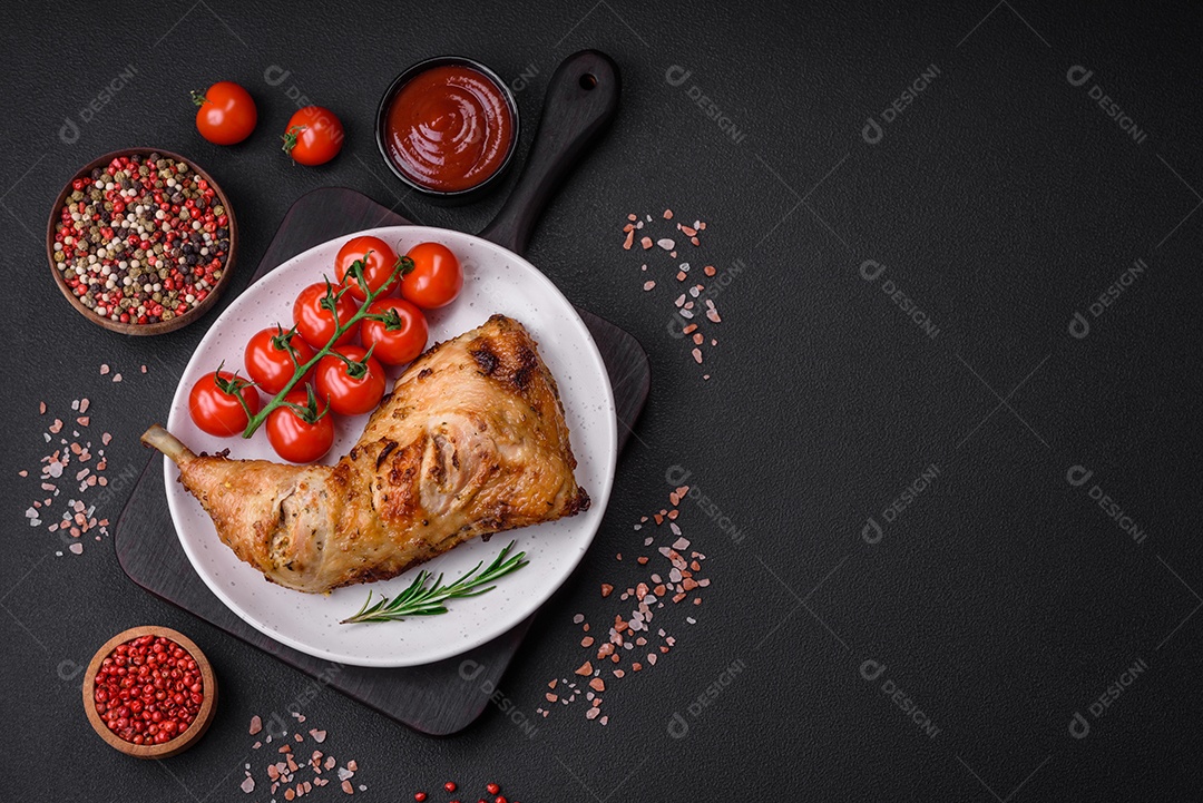 Perna de frango grelhado fresco com sal, especiarias e ervas sobre um fundo escuro de concreto