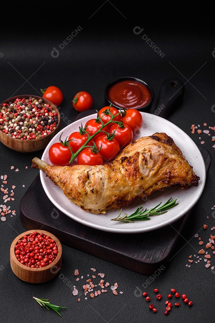 Perna de frango grelhado fresco com sal, especiarias e ervas sobre um fundo escuro de concreto