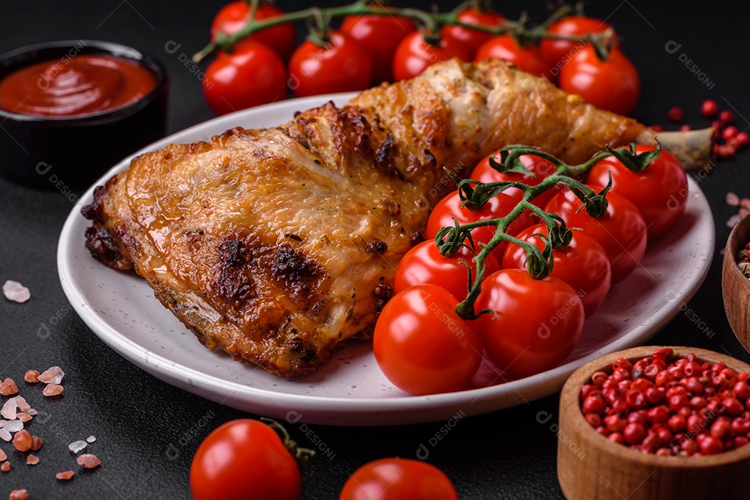 Perna de frango grelhado fresco com sal, especiarias e ervas sobre um fundo escuro de concreto