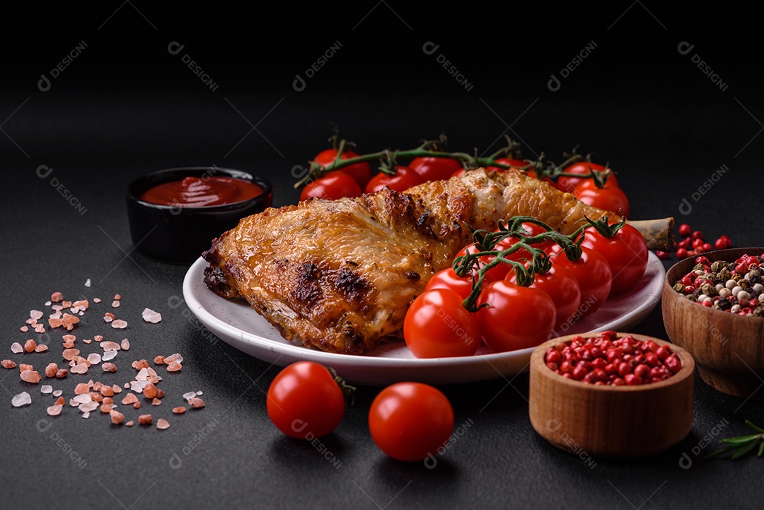 Perna de frango grelhado fresco com sal, especiarias e ervas sobre um fundo escuro de concreto