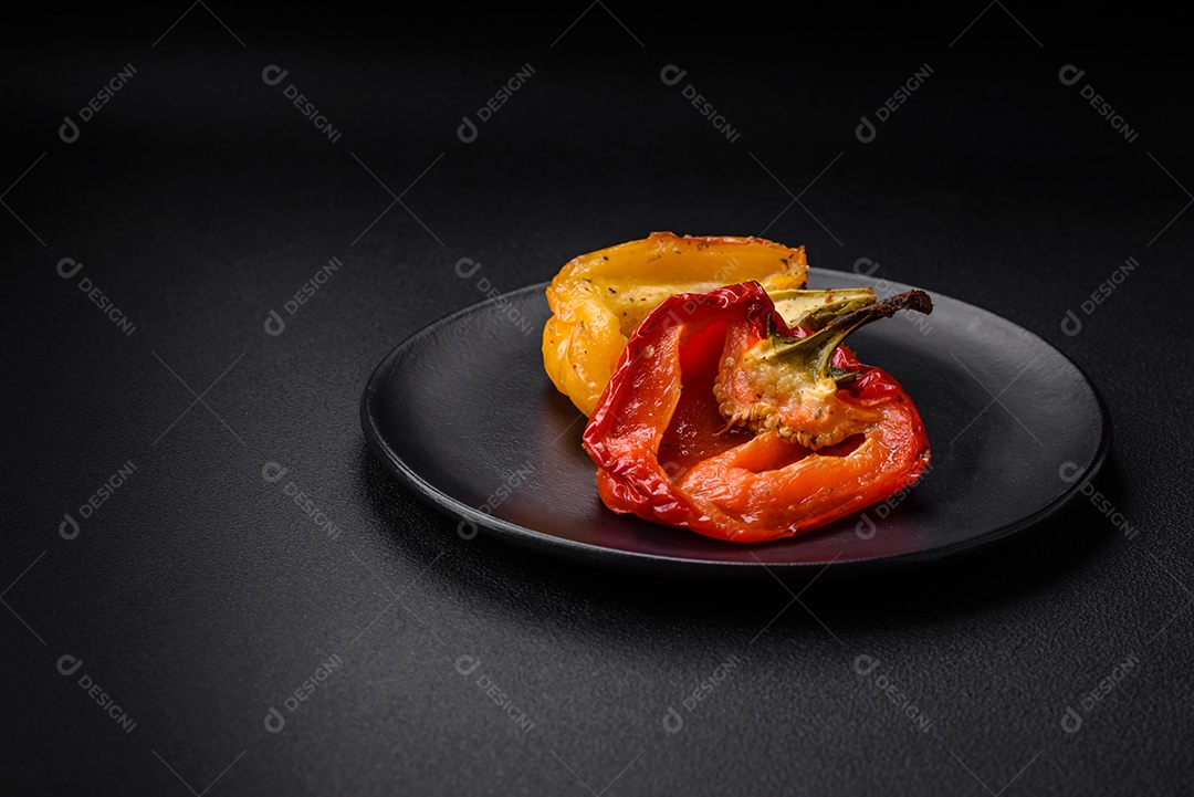 Deliciosos pimentões grelhados com especiarias e ervas em um fundo escuro de concreto