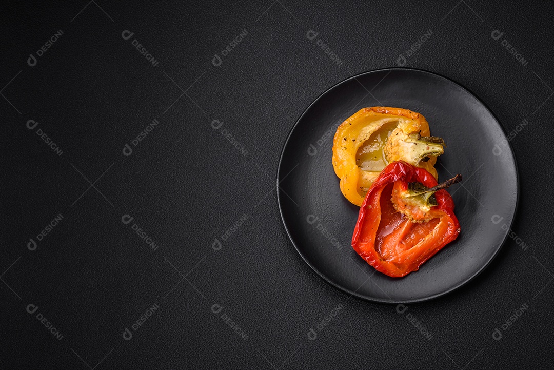 Deliciosos pimentões grelhados com especiarias e ervas em um fundo escuro de concreto