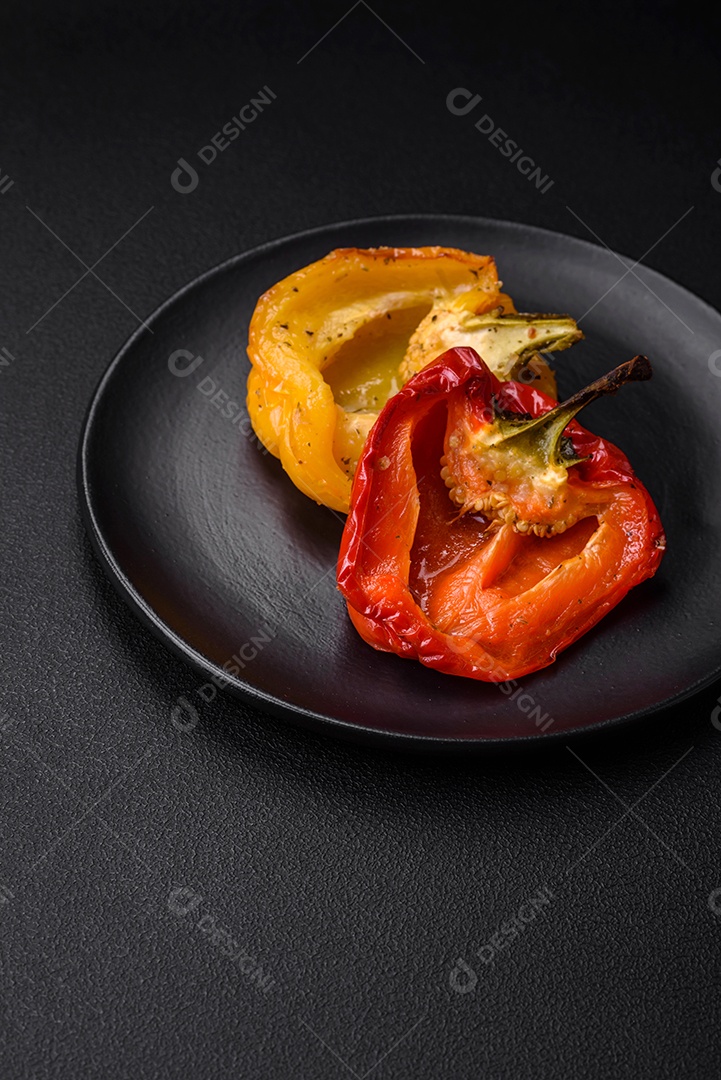 Deliciosos pimentões grelhados com especiarias e ervas em um fundo escuro de concreto