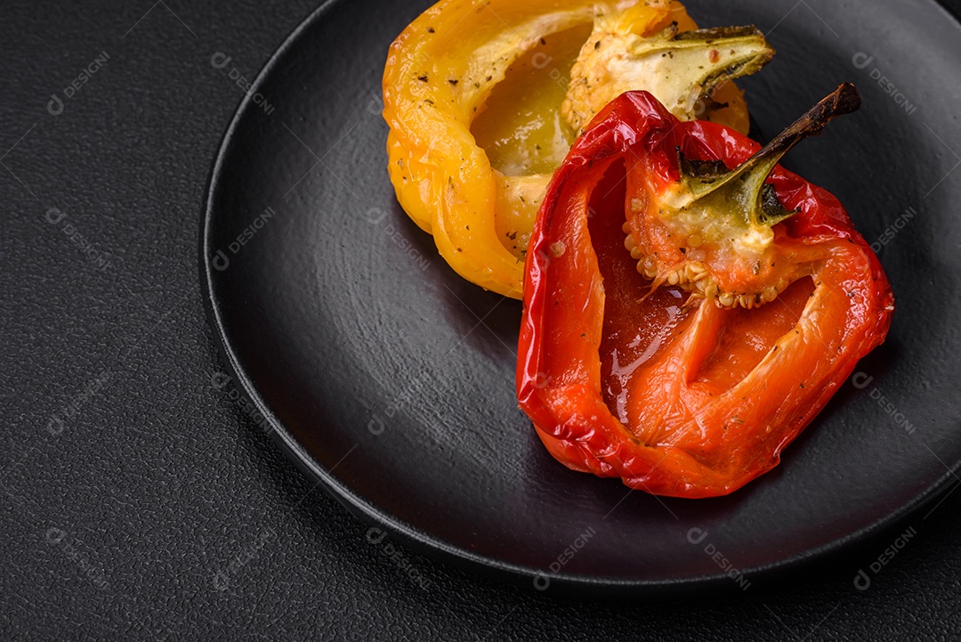 Deliciosos pimentões grelhados com especiarias e ervas em um fundo escuro de concreto