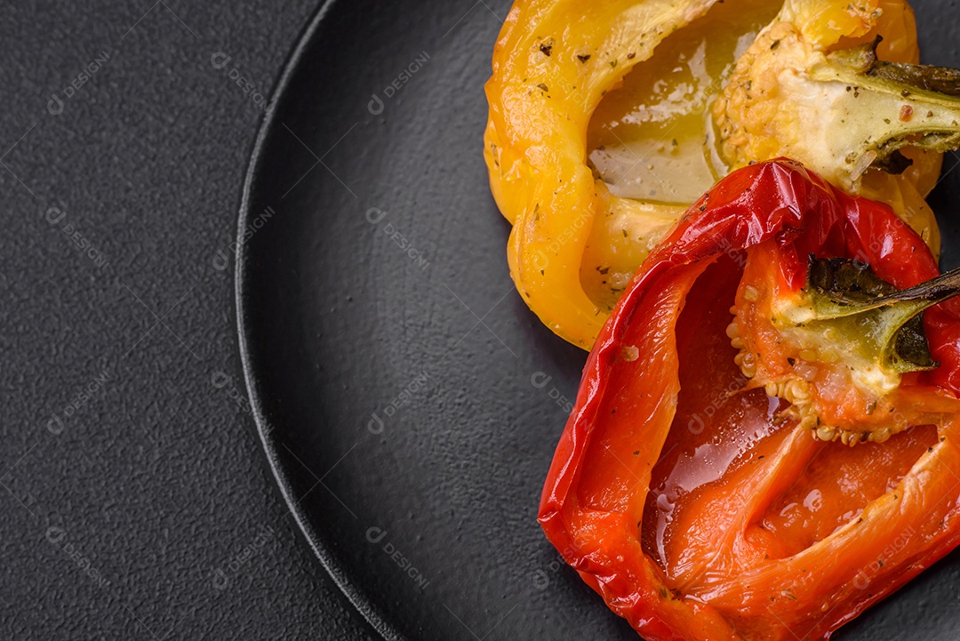 Deliciosos pimentões grelhados com especiarias e ervas em um fundo escuro de concreto