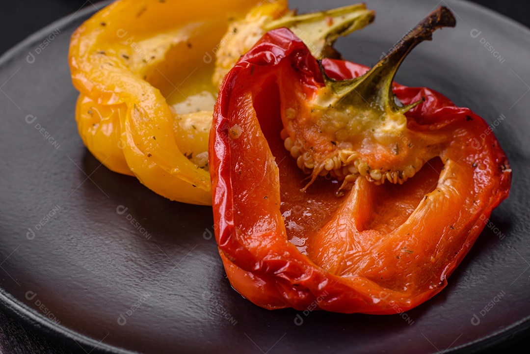 Deliciosos pimentões grelhados com especiarias e ervas em um fundo escuro de concreto