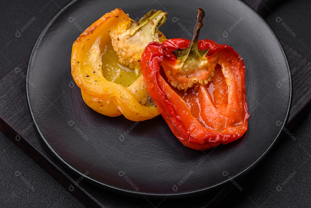 Deliciosos pimentões grelhados com especiarias e ervas em um fundo escuro de concreto