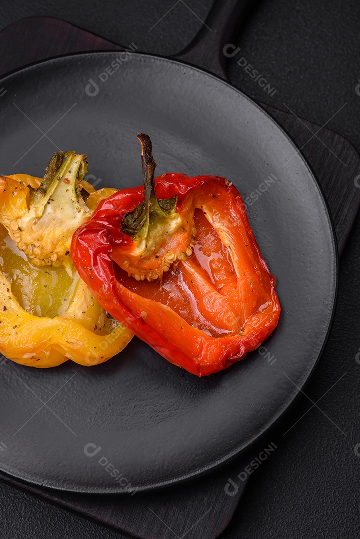 Deliciosos pimentões grelhados com especiarias e ervas em um fundo escuro de concreto