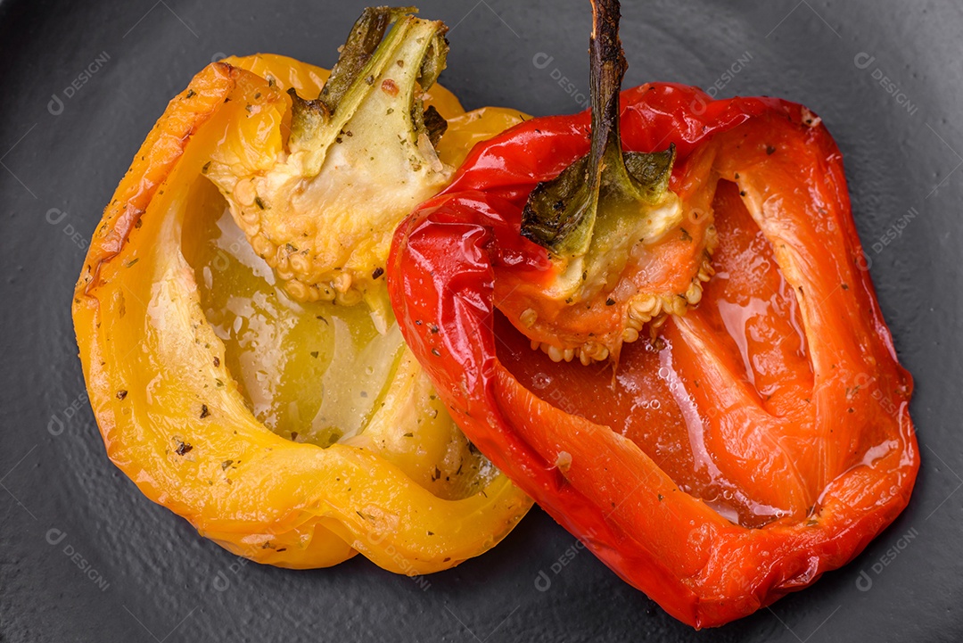 Deliciosos pimentões grelhados com especiarias e ervas em um fundo escuro de concreto