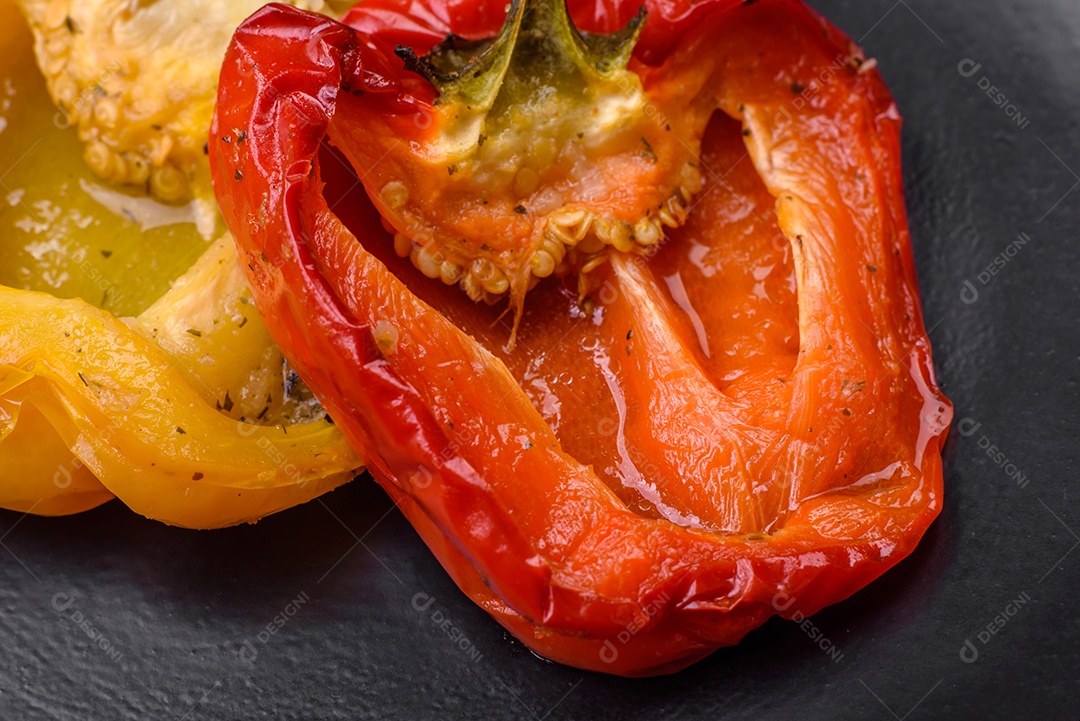 Deliciosos pimentões grelhados com especiarias e ervas em um fundo escuro de concreto