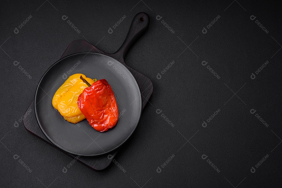 Deliciosos pimentões grelhados com especiarias e ervas em um fundo escuro de concreto