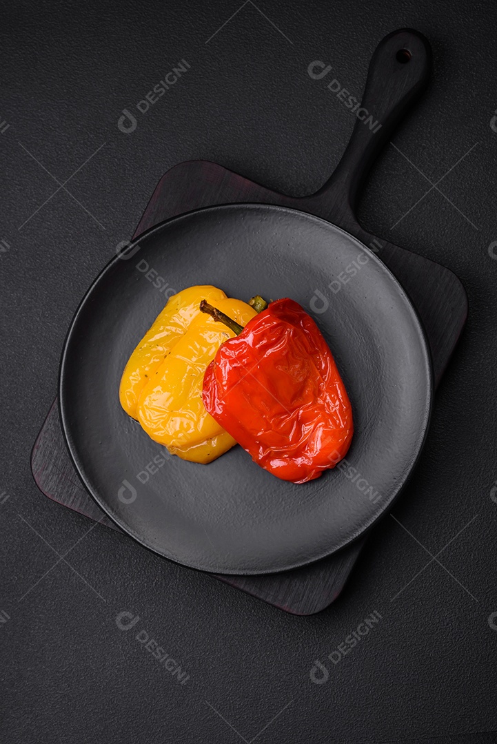 Deliciosos pimentões grelhados com especiarias e ervas em um fundo escuro de concreto