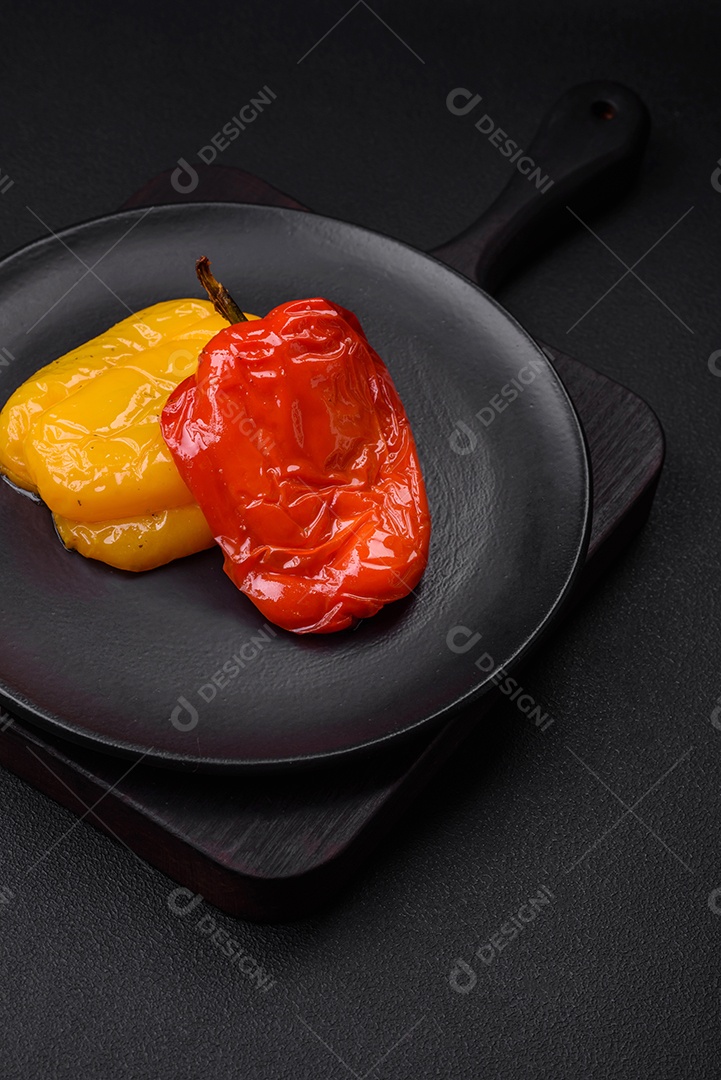 Deliciosos pimentões grelhados com especiarias e ervas em um fundo escuro de concreto