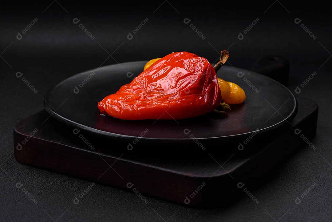 Deliciosos pimentões grelhados com especiarias e ervas em um fundo escuro de concreto