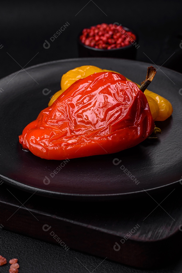 Deliciosos pimentões grelhados com especiarias e ervas em um fundo escuro de concreto