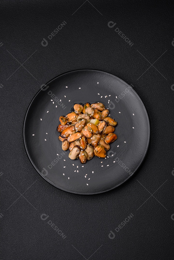 Deliciosos mexilhões marinados com especiarias e ervas em uma placa cerâmica sobre um fundo escuro de concreto