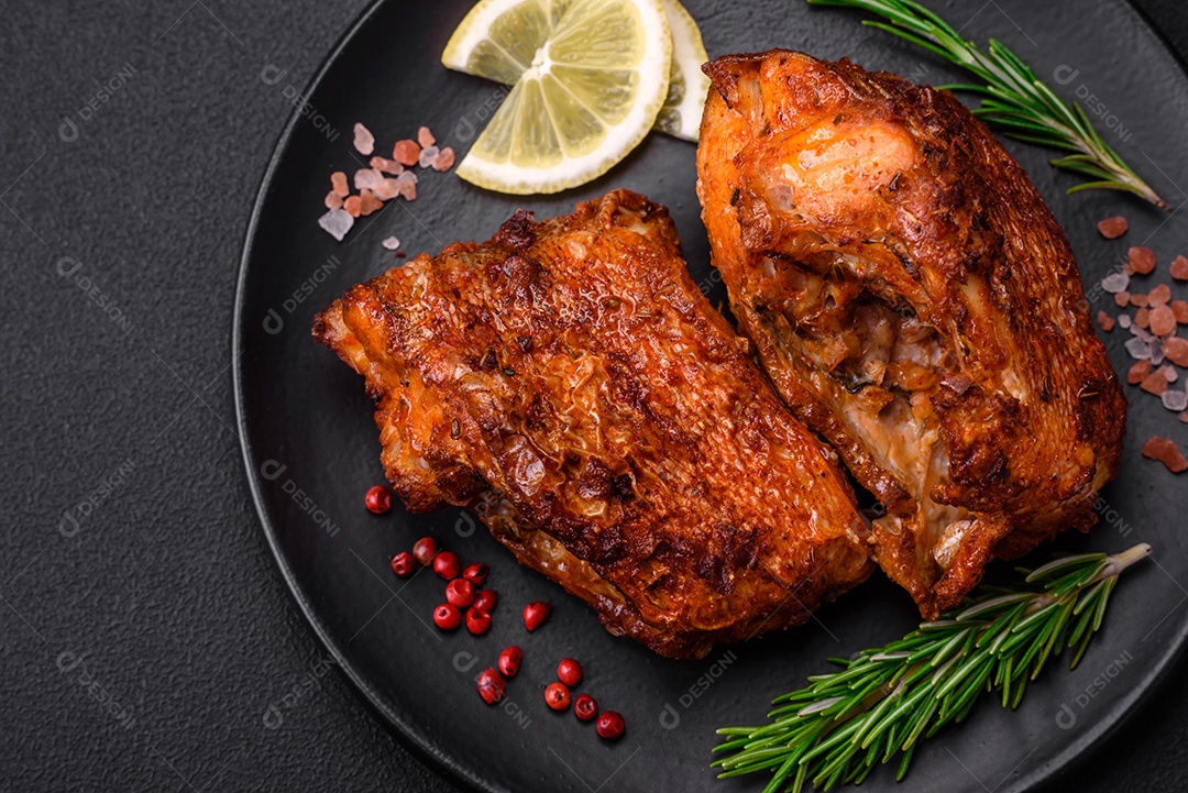 Delicioso robalo frito em forma de fatias com especiarias e ervas em uma placa cerâmica sobre um fundo escuro de concreto