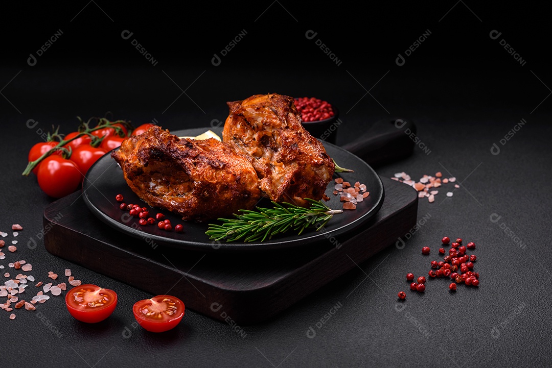 Delicioso robalo frito em forma de fatias com especiarias e ervas em uma placa cerâmica sobre um fundo escuro de concreto