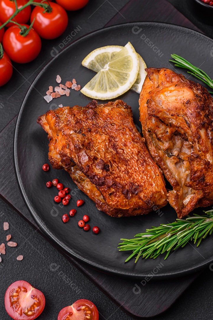 Delicioso robalo frito em forma de fatias com especiarias e ervas em uma placa cerâmica sobre um fundo escuro de concreto