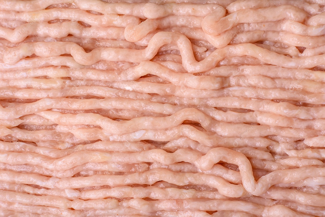 Frango picado fresco com sal, especiarias e ervas em uma tábua de madeira sobre um fundo escuro de concreto