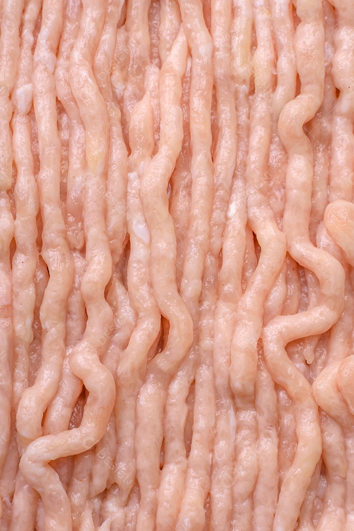 Frango picado fresco com sal, especiarias e ervas em uma tábua de madeira sobre um fundo escuro de concreto