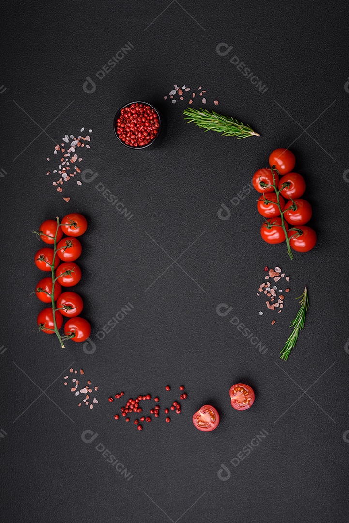 Mesa vazia de textura preta, tomate cereja em um galho, especiarias, sal e ervas. Ingredientes para cozinhar em casa