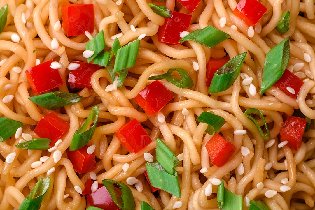 Delicioso macarrão asiático fresco com legumes, sal, especiarias e ervas em uma placa cerâmica sobre um fundo escuro de concreto